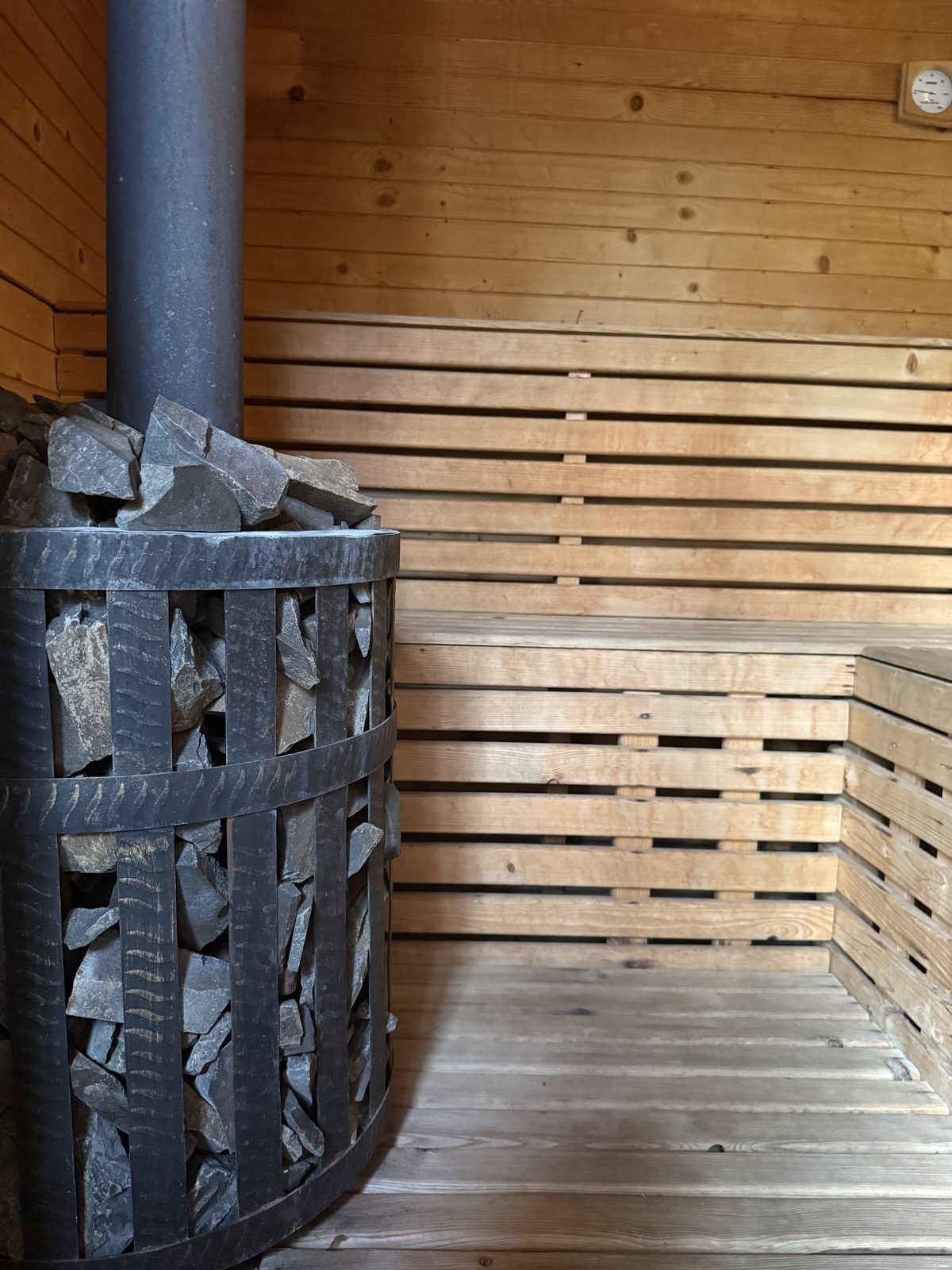 Sauna: piec w koszu z kamieni i drewniane ławy